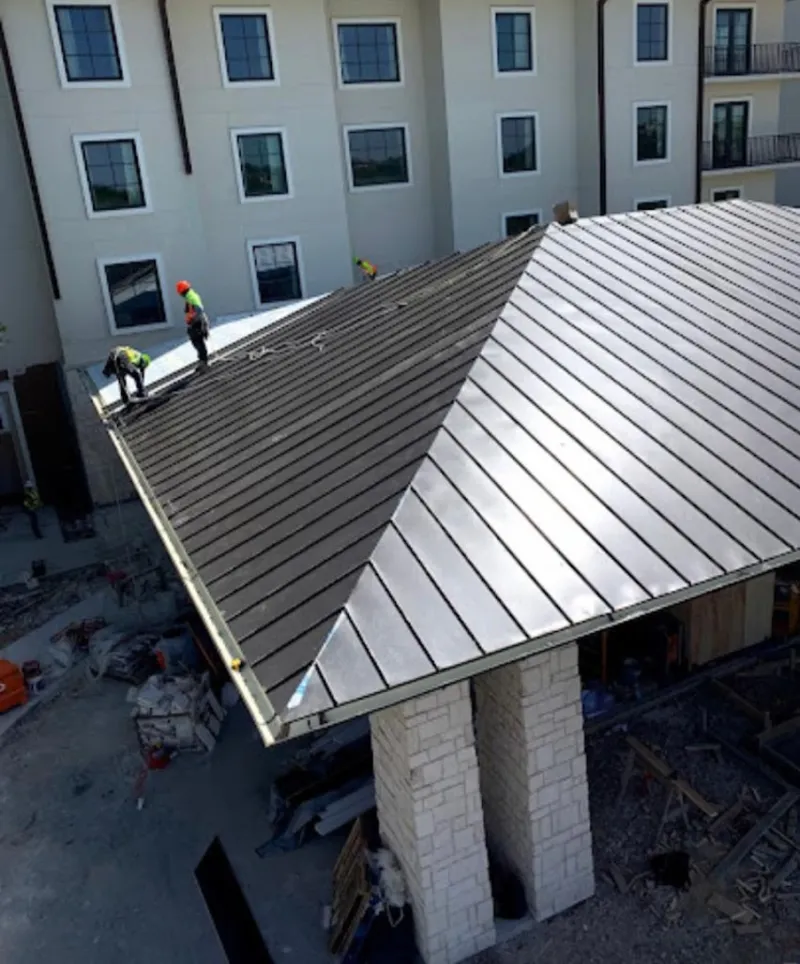 Crew installing standing seam metal roof panels on a commercial project in Hilmar-Irwin